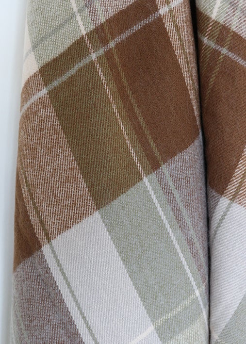 Close-up of plaid fabric with brown, beige, and gray colors on a white background
