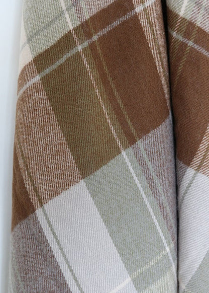 Close-up of plaid fabric with brown, beige, and gray colors on a white background