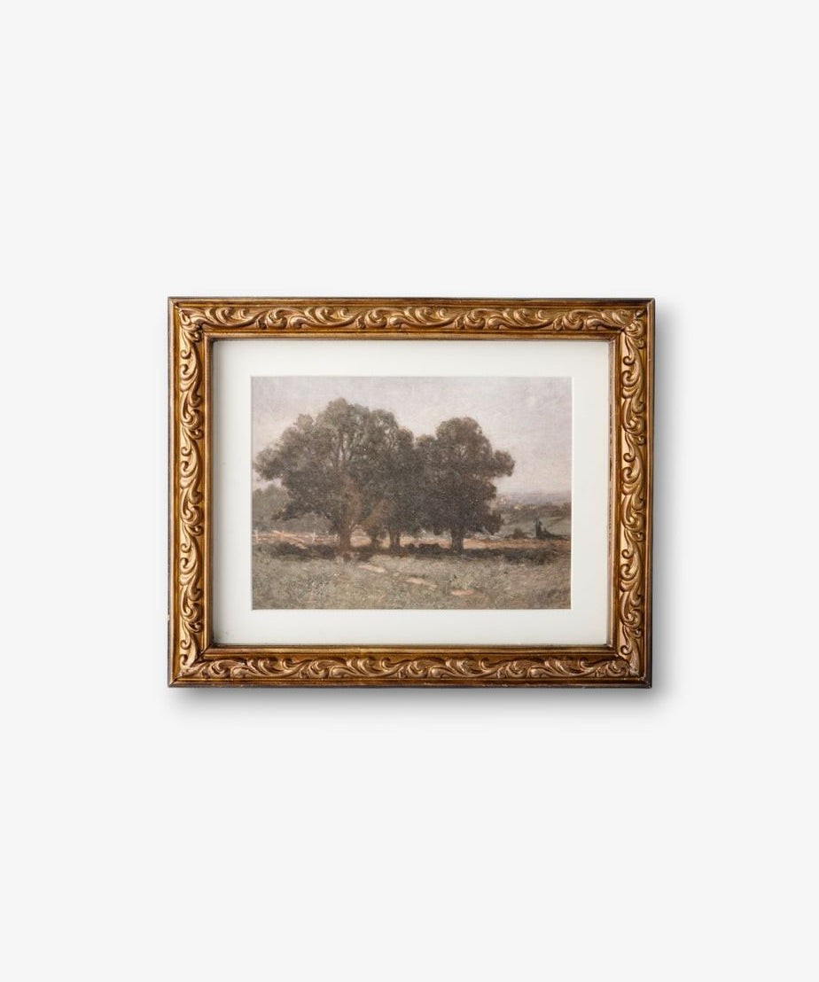Framed artwork of a landscape with trees on a white wall