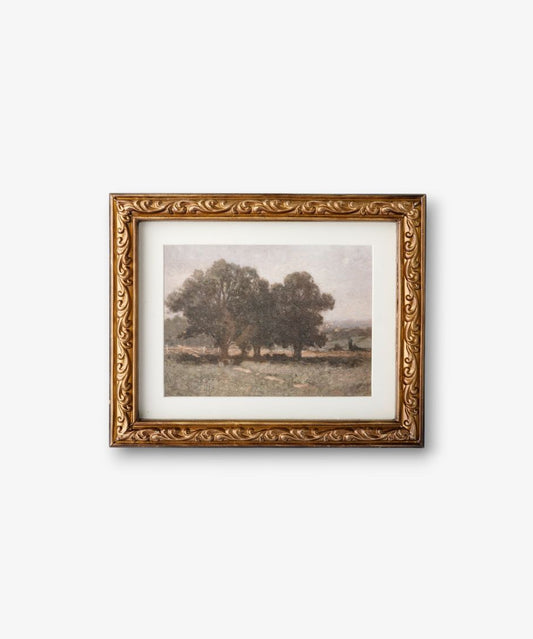 Framed artwork of a landscape with trees on a white wall
