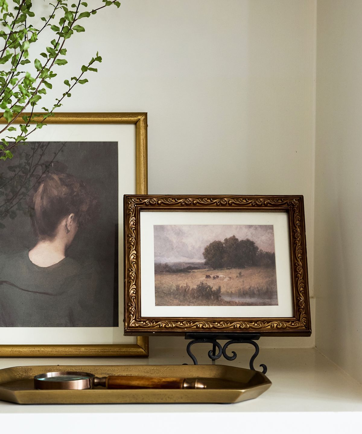 Two framed artworks on a stand with a decorative tray below.